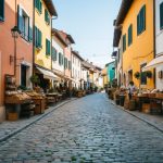 A cobblestone street winds through a quaint European village, lined with colorful, centuries-old buildings and bustling with artisanal workshops and markets